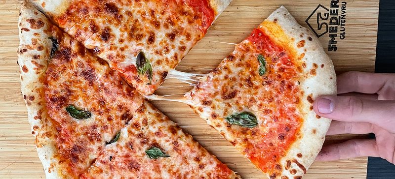 Een punt margherita wordt uit de pizza getrokken, met lange draden gesmolten kaas