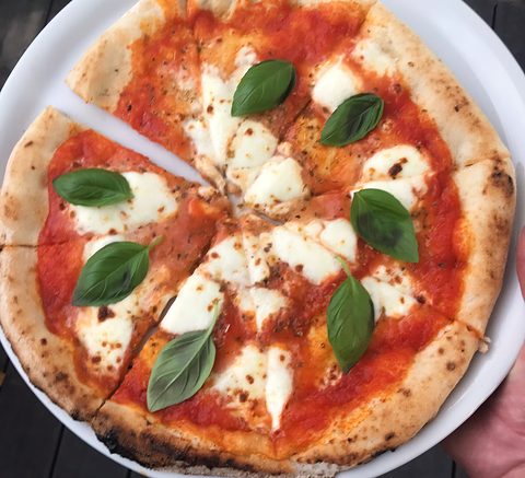 Margherita met tomatensaus, verse mozzarella en blaadjes basilicum, in punten gesneden
