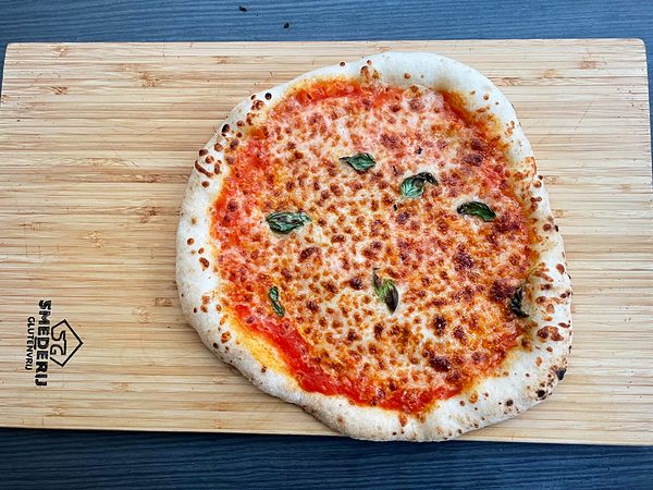 Margherita met basilicum op een bamboe plank met het logo van Smederij Glutenvrij