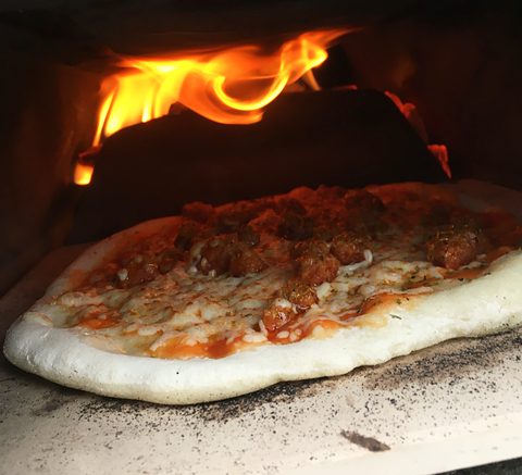 Pizza in de oven, met vlammen achteraan